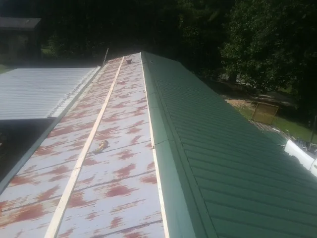 Old rusted panels beside newly installed green metal roofing — Wind Damage Roof Repair by Roofing Brothers in Horseheads