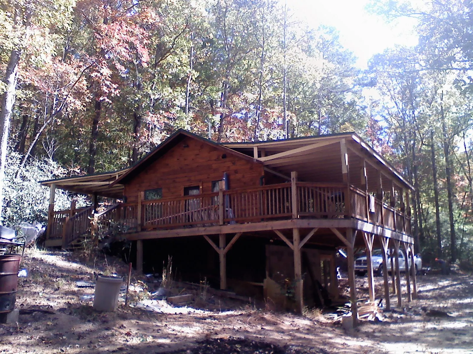 Log cabin with a wraparound porch and metal roof in the fall in Horseheads