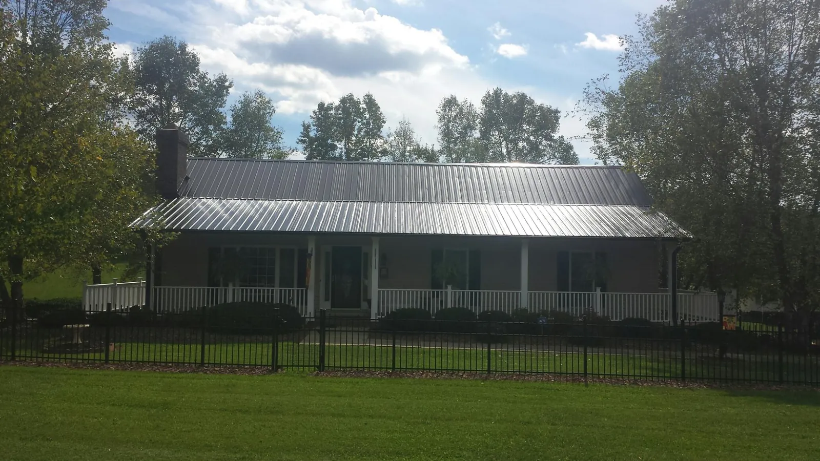 Gray metal roof on a brick ranch with a full width front porch — Gutter Guard Installation work by our crew in Horseheads