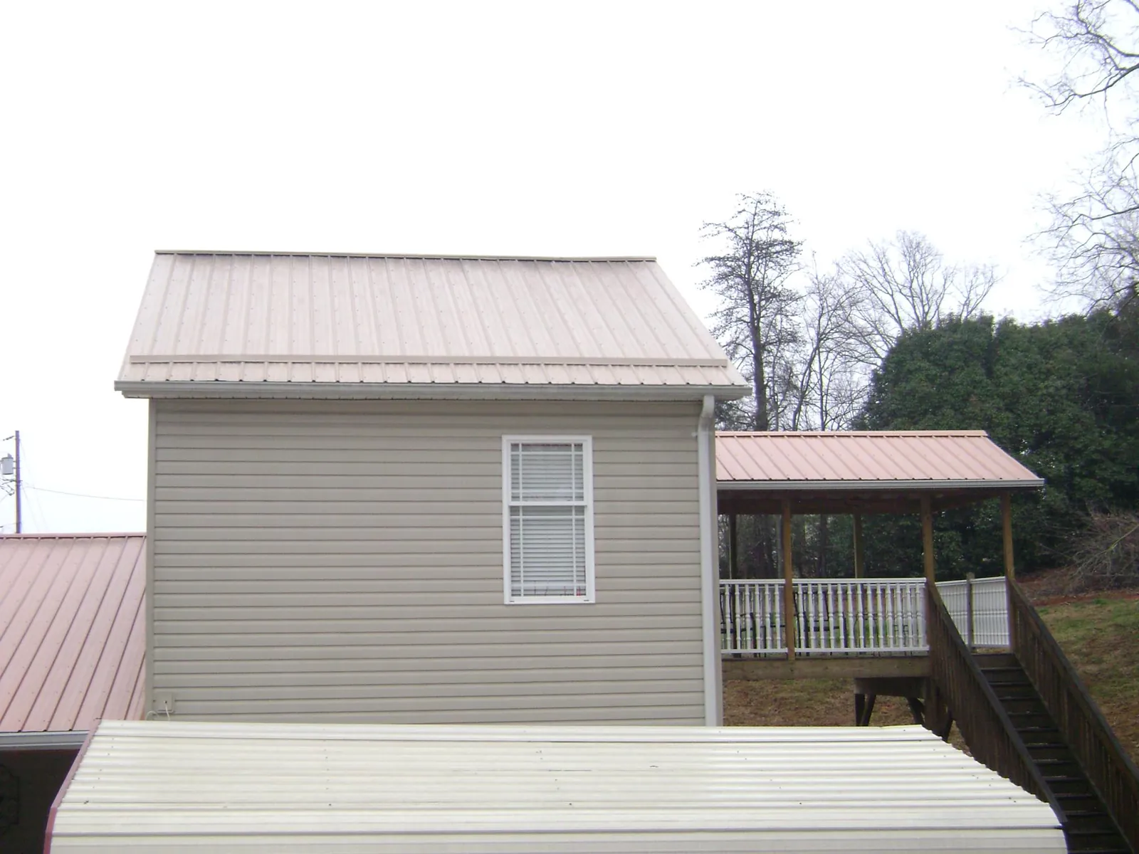 Tan metal roofs on a two story addition and attached porch, from a Roof Replacement job in Horseheads