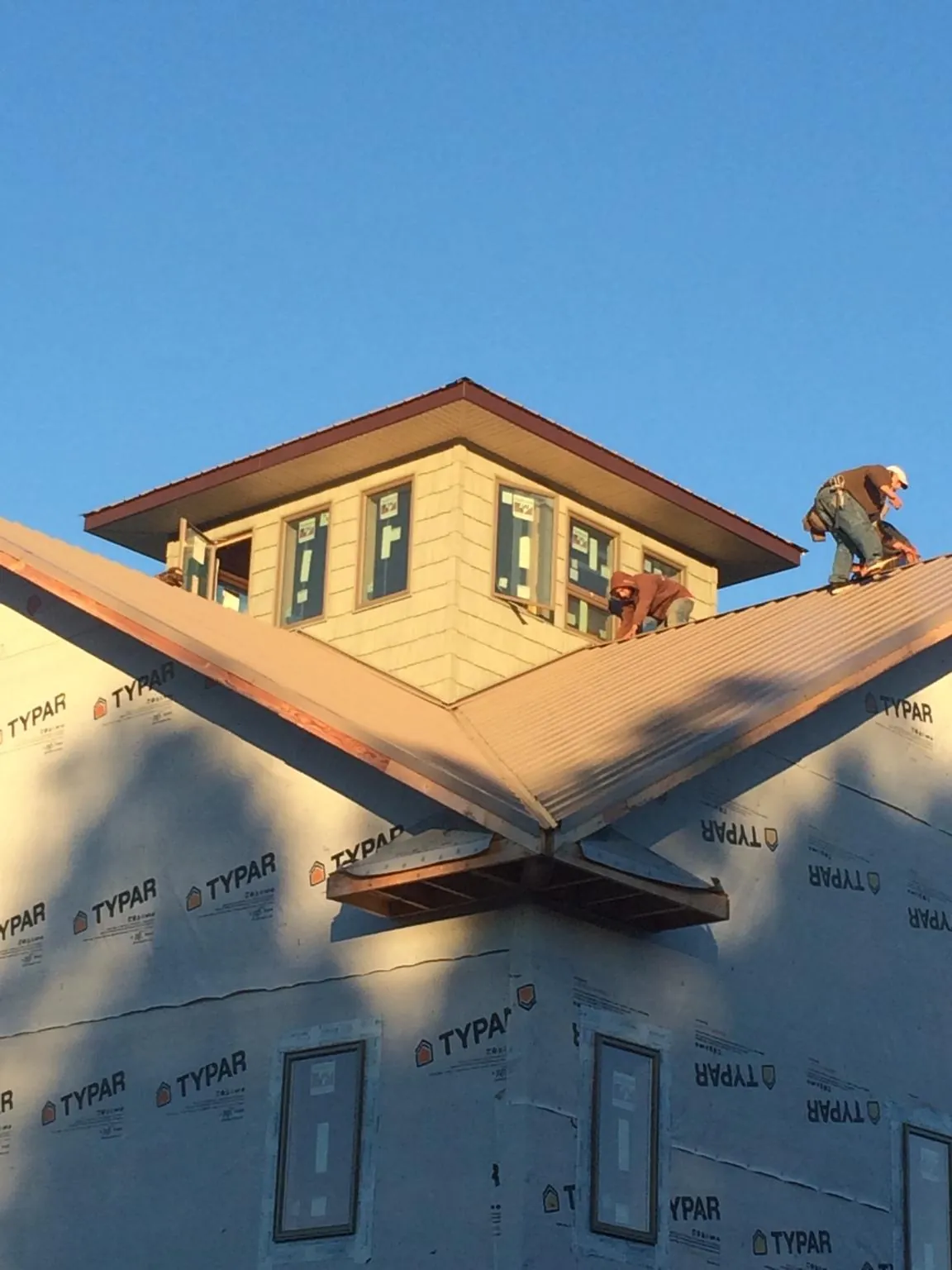 Roofers working around a rooftop cupola on a new metal roof at sunset — Roof Waterproofing in Horseheads by Roofing Brothers